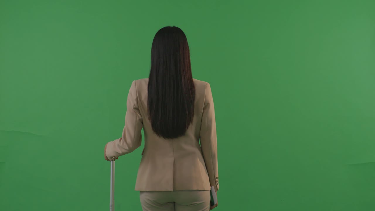 뒷면 동양 사업가 여성 여행자 수하물과 함께 산책하고 서 있는 초록색 스크린 배경 스튜디오, 일몰 시간