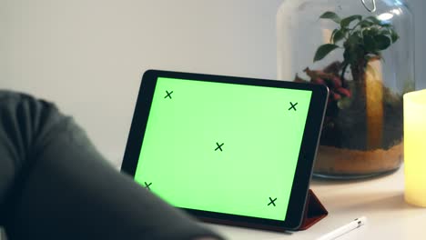 young man looking at tablet with green screen enoying cup of tea