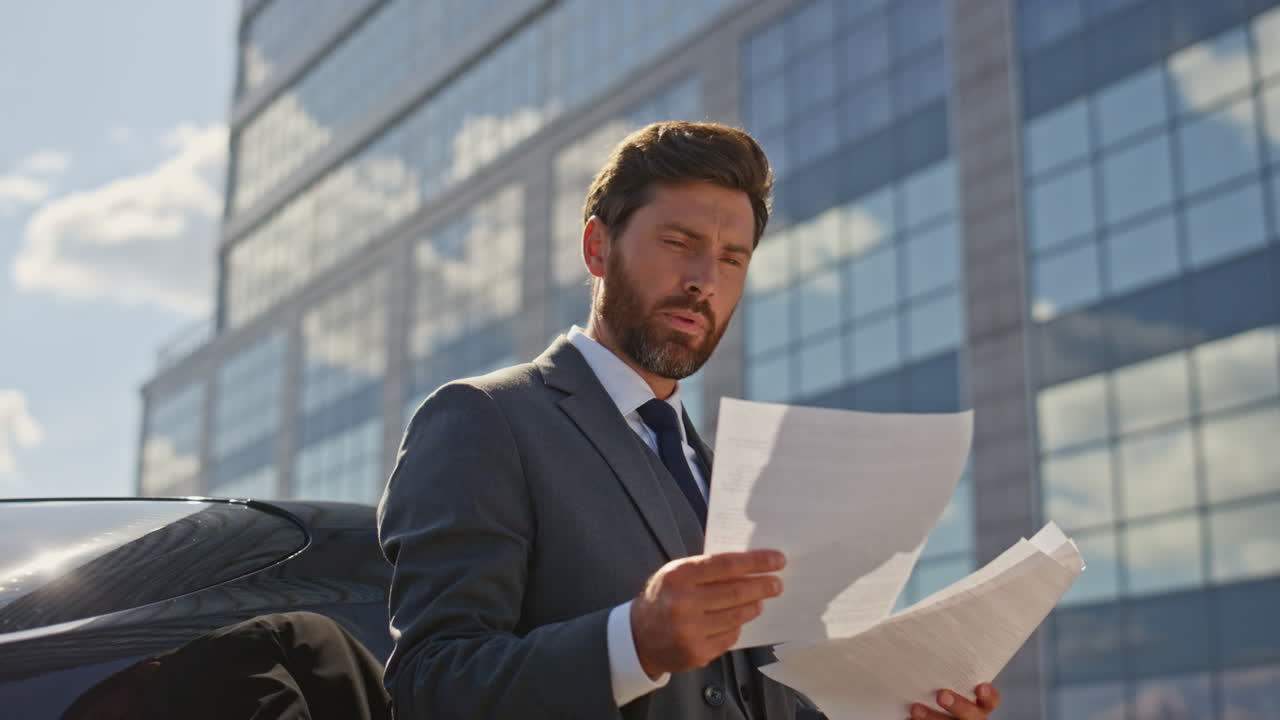 Thoughtful director reading contract at sunny business area. Boss looking deal