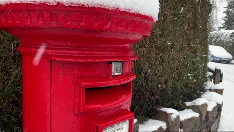 posting christmas cards and letters into a red mail box in winter