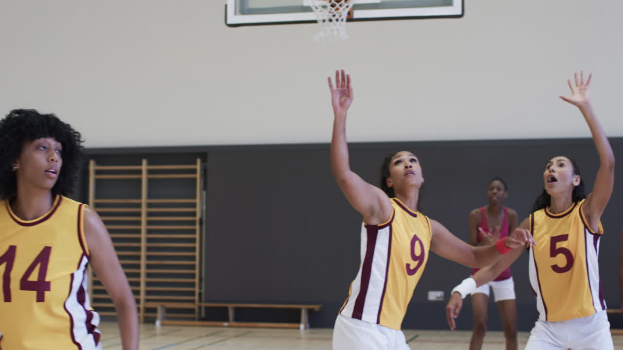 un grupo diverso de amigas juega al baloncesto en un gimnasio