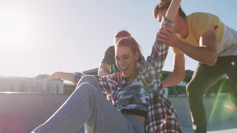 laughing caucasian woman and two male friends, skateboarding on sunny day