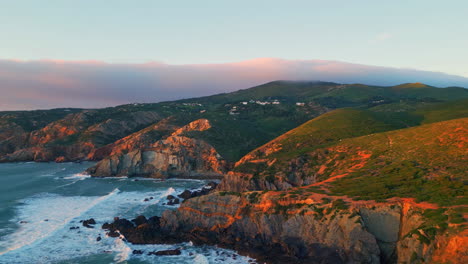 foaming sea hitting cliffs sunny day slow motion. aerial green hills ocean waves