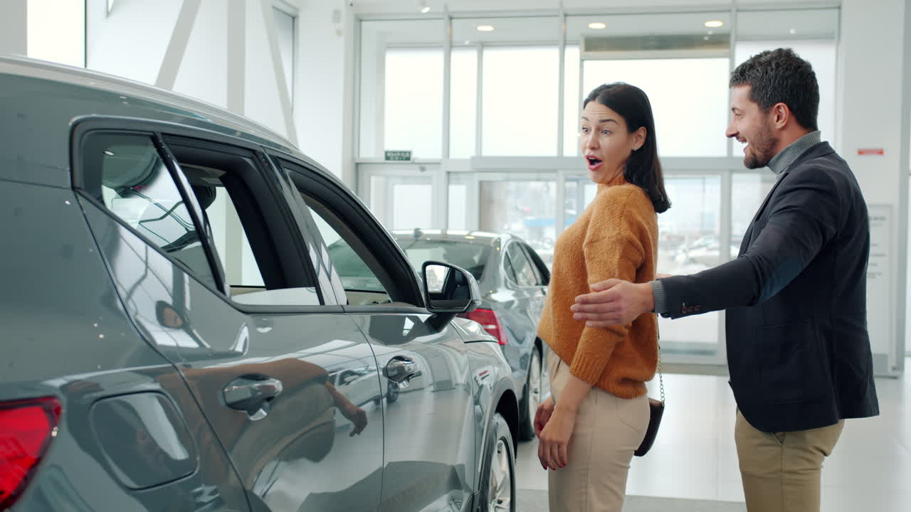 una pareja mirando un coche en una sala de exposiciones