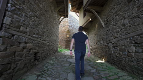 young man walking along the ancient homes in the kovachevitsa village in garmen, blagoevgrad province, bulgaria. - follow shot