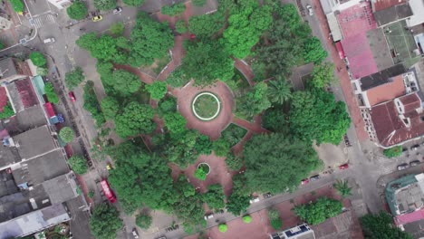 top-down zoom out view of circular garden and tree-lined walkways in a public park in yopal, colombia