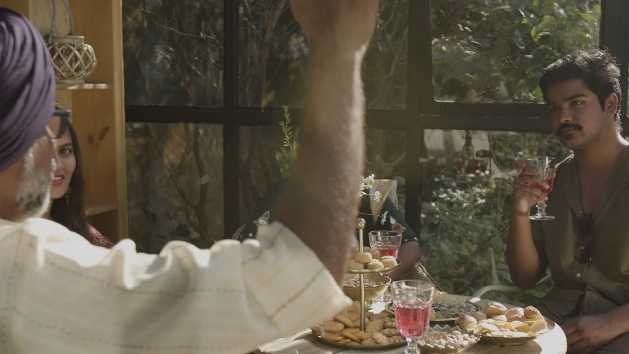 Friends and family enjoying a social gathering with drinks and snacks in a sunny outdoor setting