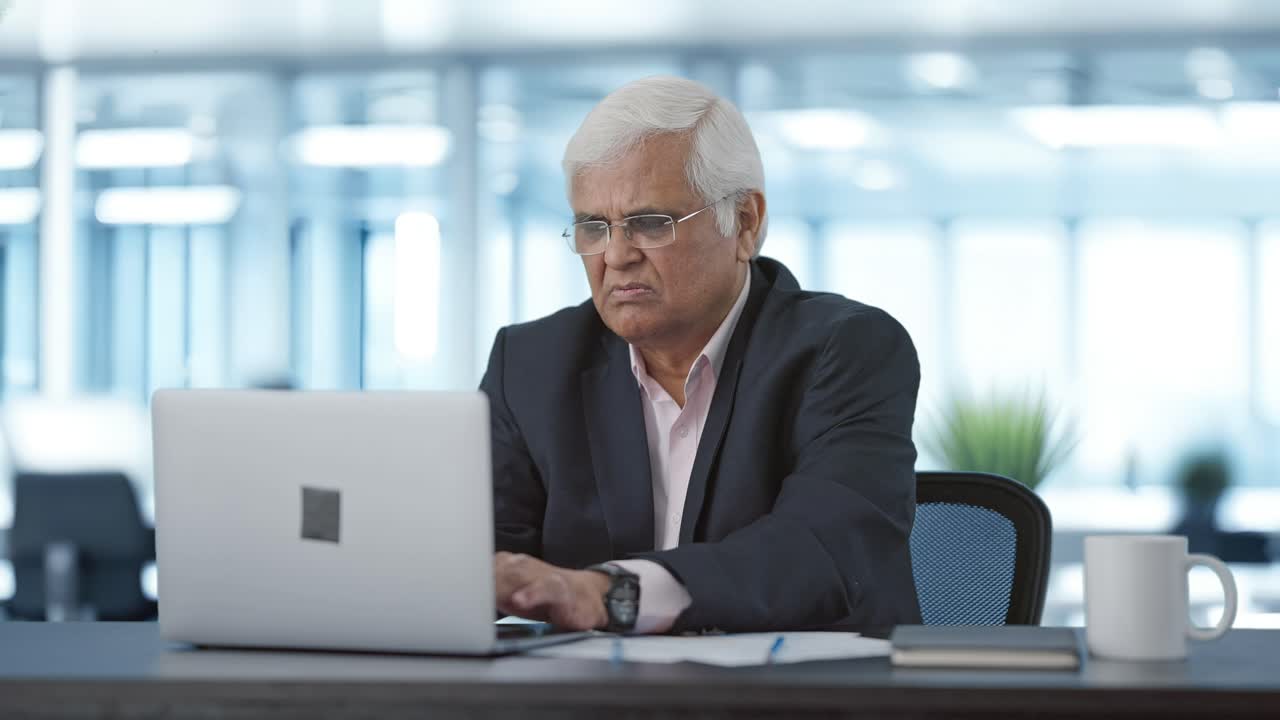 Confuso e serio anziano manager indiano che lavora al laptop