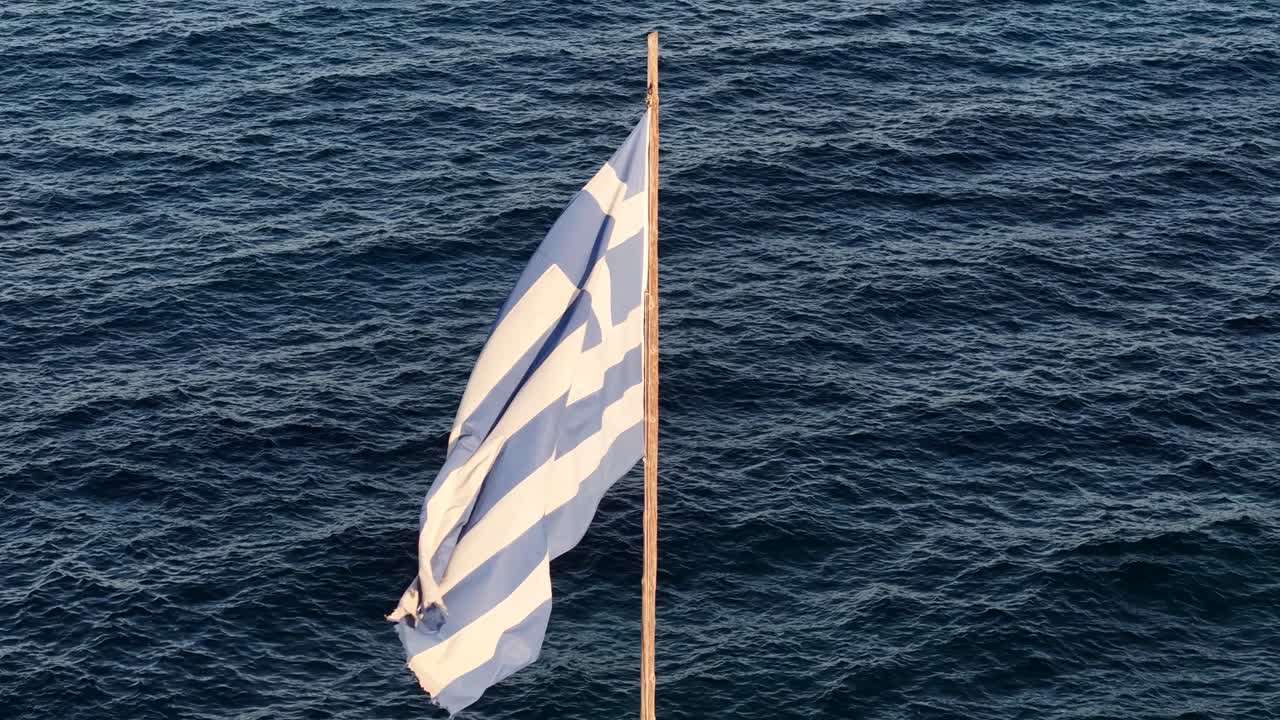National Flag of Greece Waving on Pole at Coats Above Sea, Drone Aerial View