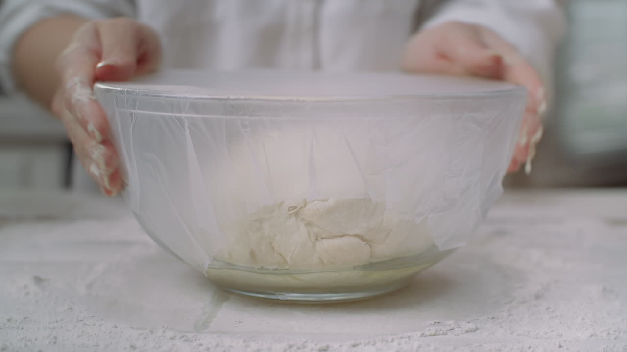 covering pizza dough in a bowl to allow time for it to rise