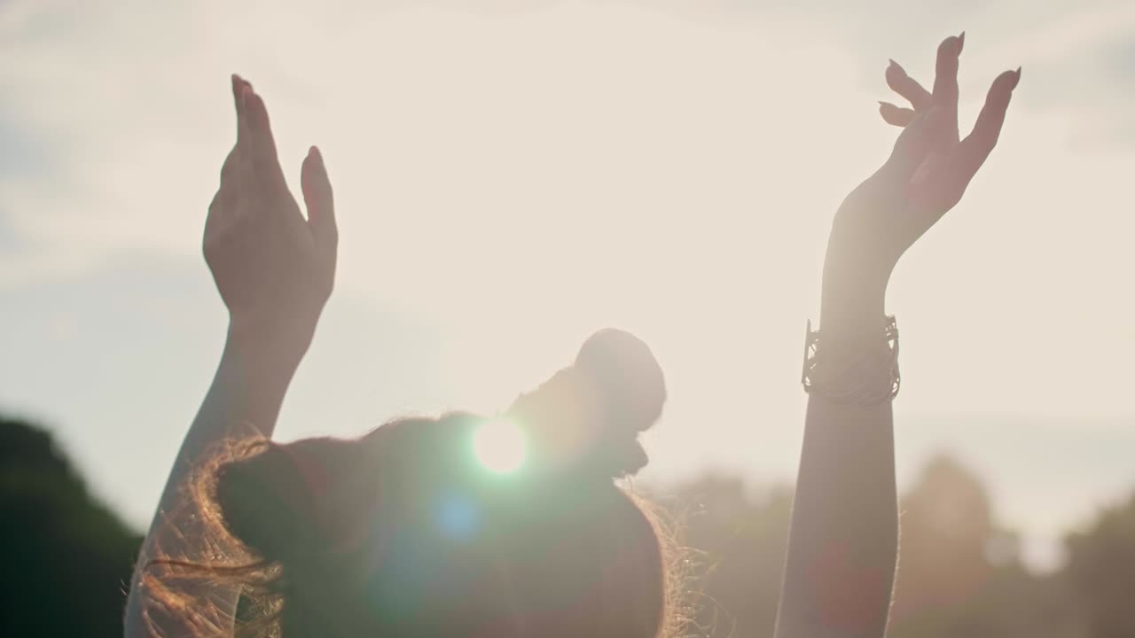 手を挙げて屋外で踊っている女性の後ろの景色