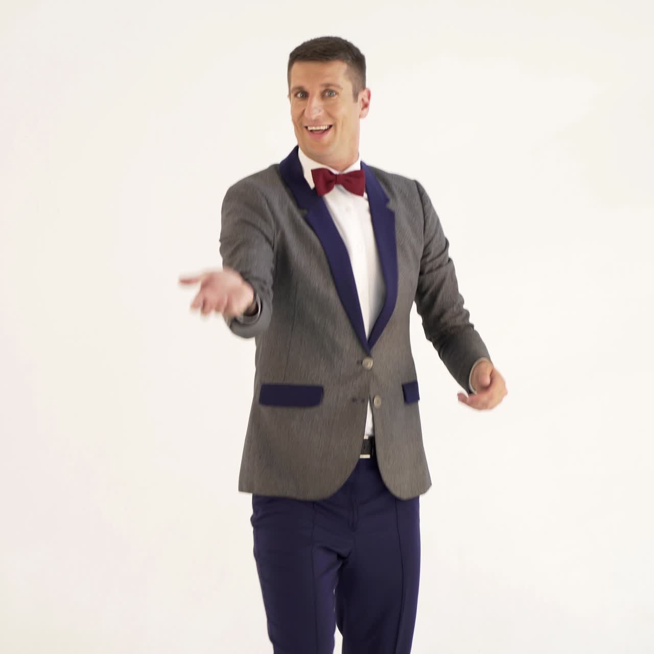 a man in a gray and blue colours of suit is juggling as a clown in the studio. Parody of a funny clown in a circus