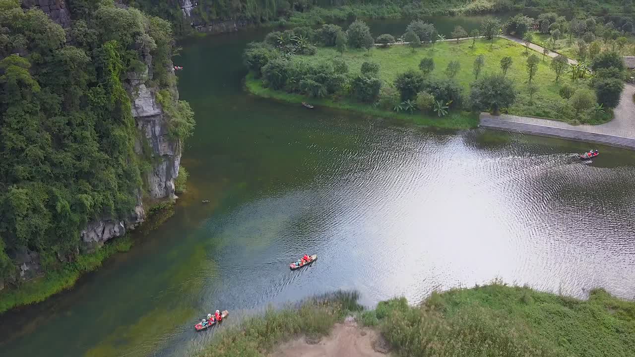 Filmato aereo con drone di vette calcaree verdi e maestose. Risaie nella giungla selvaggia in primavera con gita in barca sul canale a Trang An, Ninh Binh, Vietnam