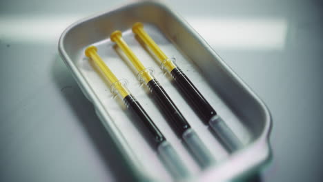 syringes with a dark liquid on a medical tray