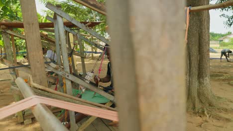 un hombre de ghana tejiendo manualmente recuerdos de kente en un telar de madera en cámara lenta