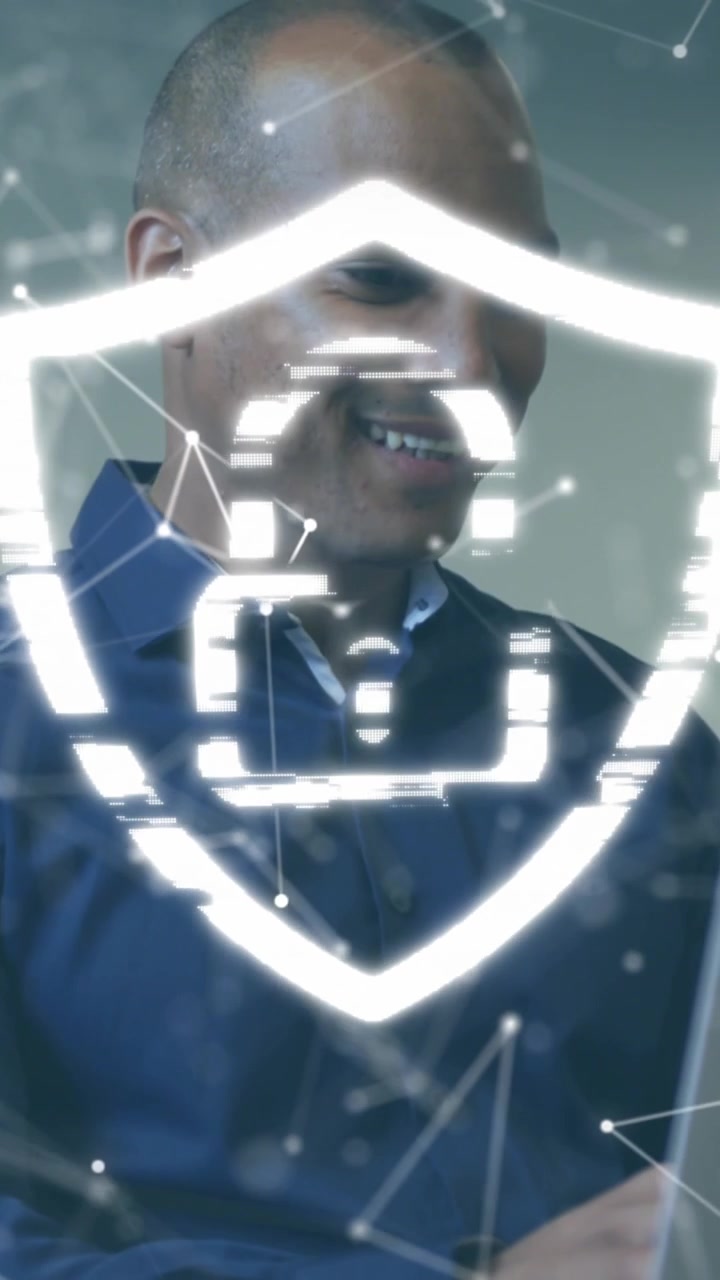 Animation of padlock in shield, connected dots over african american businessman working on laptop