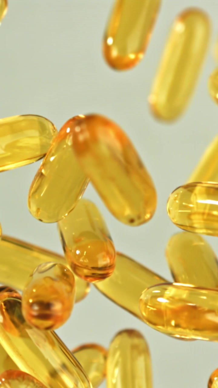 Capsule softgel Omega-3 dorate che galleggiano e si mettono a fuoco