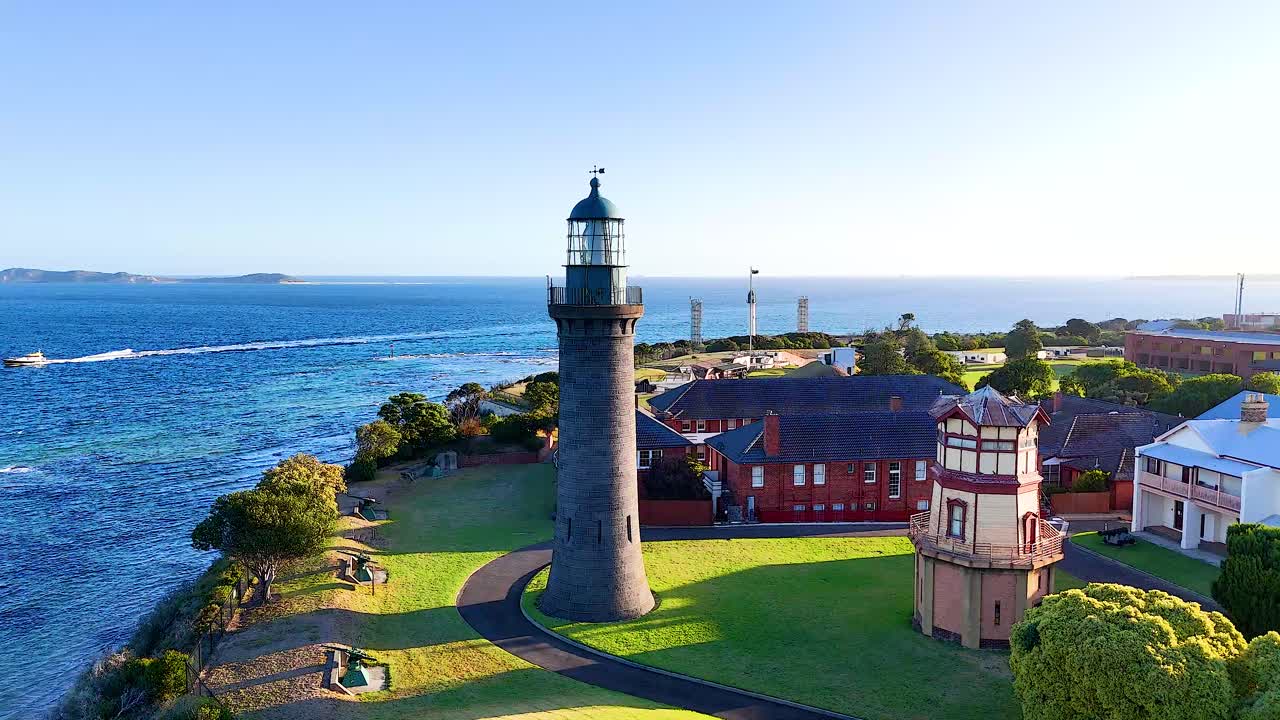 Aerial footage captures Queenscliff Lighthouse, lush greenery, and ocean views under bright daylight on Bellarine Peninsula, Victoria