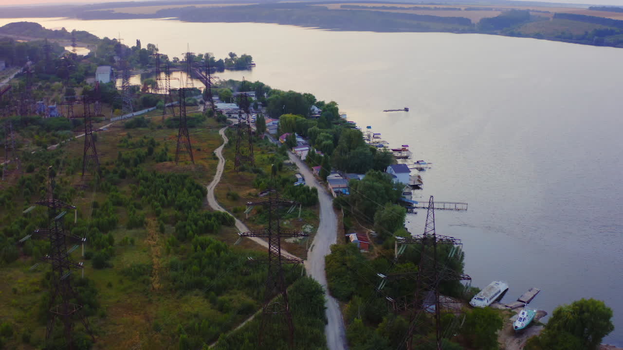 High-voltage power lines in nature. Transmission towers near the river. Electricity pylons tower at sunset. Energy efficiency concept.