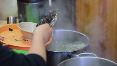 transferring boiled clams from pot to plate