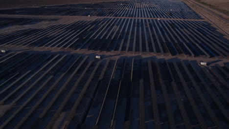 Vista-Aérea-De-La-Planta-De-Energía-Solar-Al-Atardecer,-Enormes-Conjuntos-De-Paneles-Solares,-Disparo-De-Drones