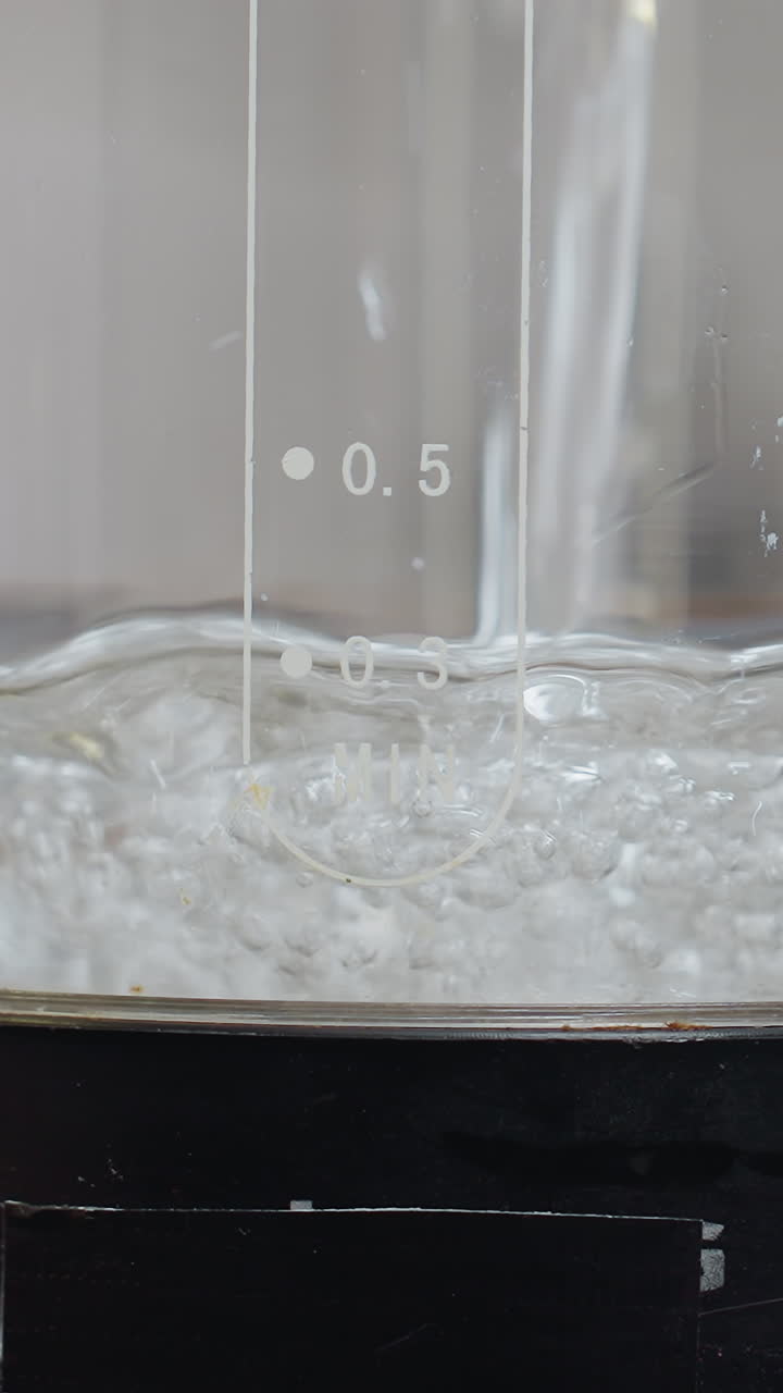 Close-up of electric water jar being filled with water, featuring inscriptions on the jar, the jar is filled with liquid, showing clear water bubbles forming, in a modern kitchen setting