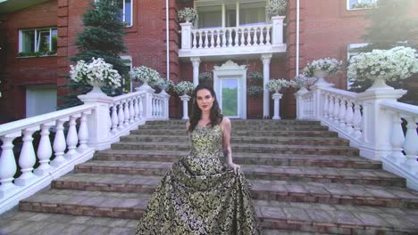 woman in a gold dress on a porch steps