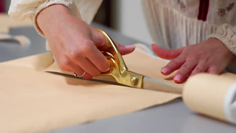 young female designer with tape-line on her neck standing in dressmaking studio and drawing lines with chalk and rule. female couturier in atelier cutting out a pattern for future clothes.