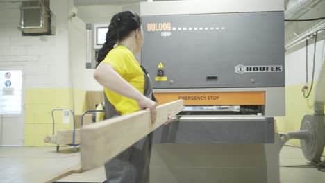 worker handling wood plank in a woodworking factory