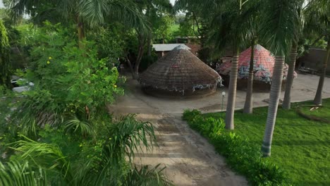 Beautiful-small-huts-and-a-house-pulling-away-shot-surrounded-by-mango-farms-in-interior-Sindh,-Pakistan