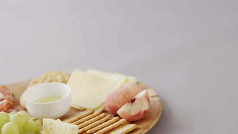 different types of cheese, crispy biscuits, fruits and sauce on wooden board