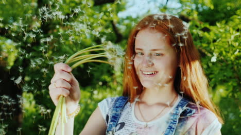 a girl with bright red hair has fun playing with dandelion flowers