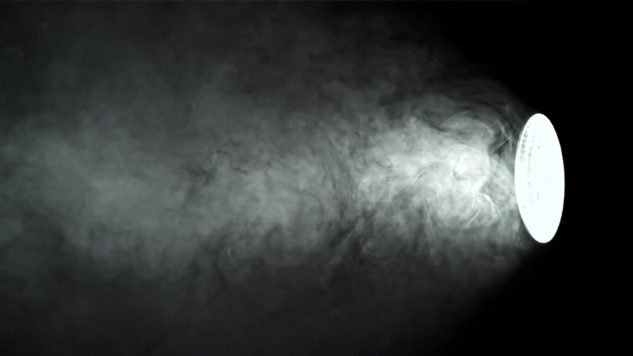 Fascio di luce che illumina fumo in movimento su sfondo nero