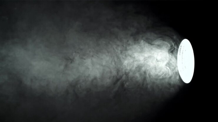 Fascio di luce che illumina fumo in movimento su sfondo nero