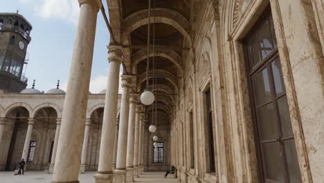 courtyard with colonnade and clock tower in background. great mosque of muhammad ali pasha or alabaster mosque, citadel of cairo in egypt. tilt down