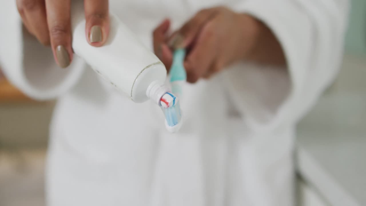 Mid section view of mixed race woman putting toothpaste on toothbrush