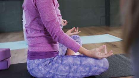 Sección-Baja-De-Mujeres-Diversas-Enfocadas-Meditando-Juntas-En-Colchonetas-En-Clase-De-Yoga,-Cámara-Lenta