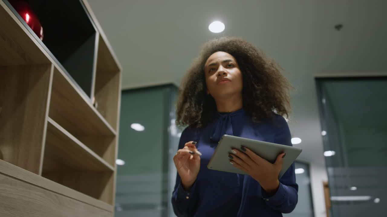 African american business woman going in office hallway browsing tablet indoors.