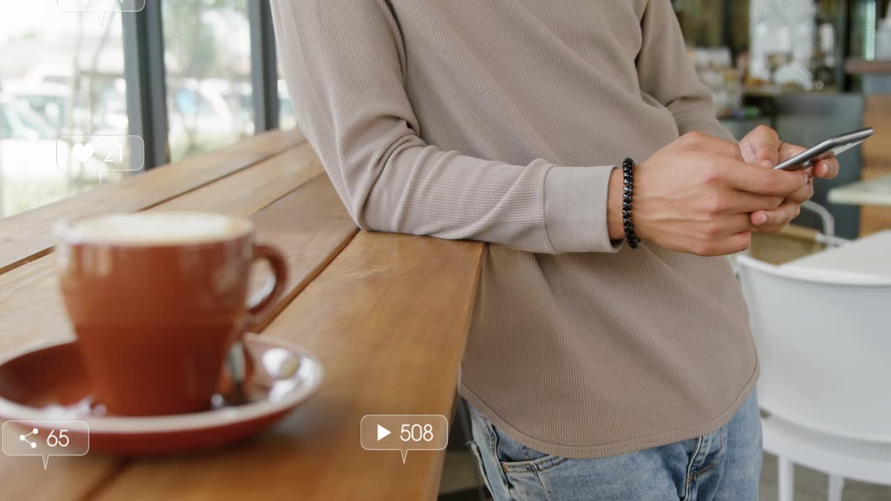 Man leaning at counter tapping phone and checking alerts, social media badges clustering around cup