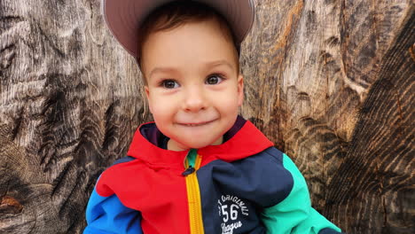 happy thoughtful baby boy sitting on the wooden sculpture. cute toddler holding a book in hands.