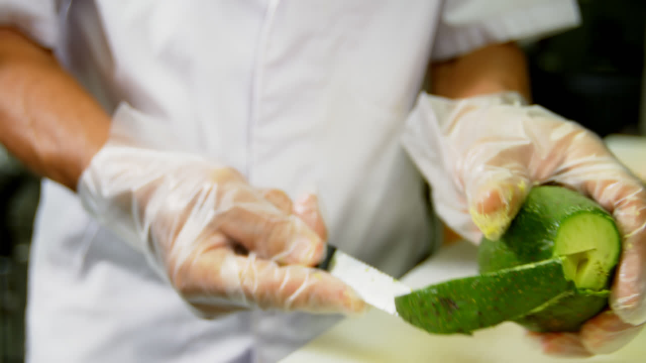 chef masculino cortando frutas de aguacate en la cocina 4k