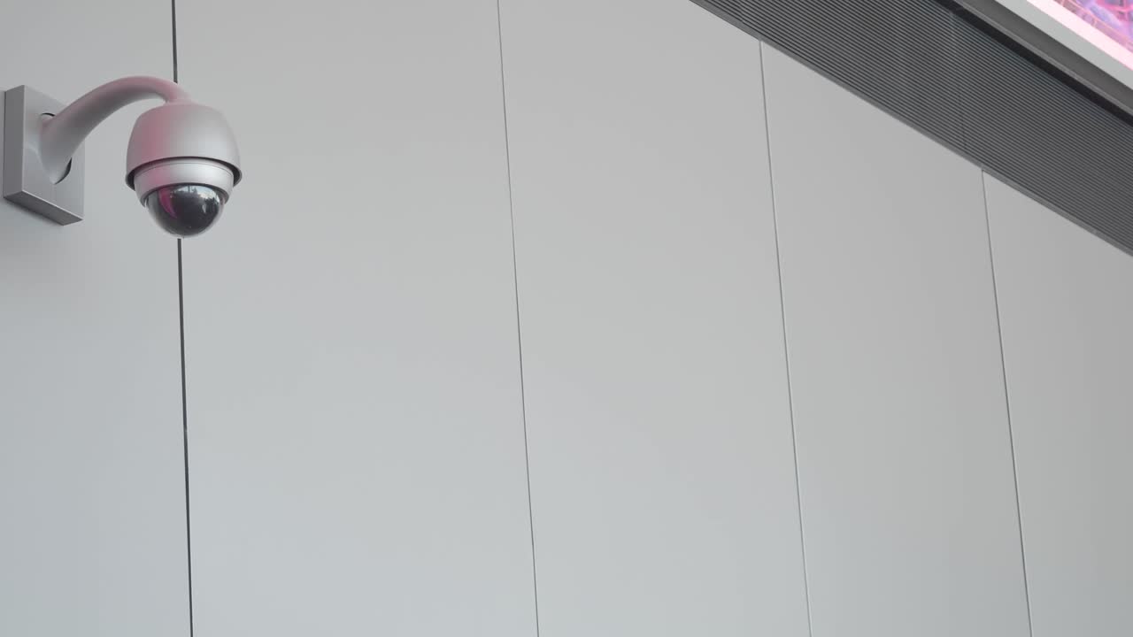 A modern security camera mounted on a grey wall
