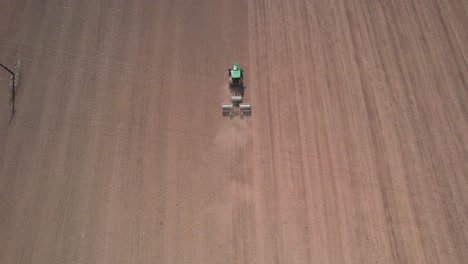 Stunning-aerial-view-of-Tractor-flattening-land-with-rollers,-rising-up-top-view