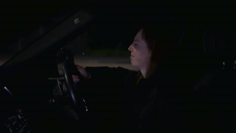 mujer feliz escuchando música en un coche estacionado al lado de una carretera concurrida por la noche