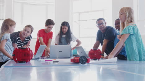 students with teachers in after school computer coding class learning to program robot vehicle