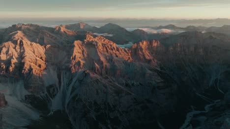 imágenes de drones empujando hacia los impresionantes picos de las montañas punta sud di fanes, punta nord y monte ciaval en las dolomitas de cortina d'ampezzo, italia al amanecer