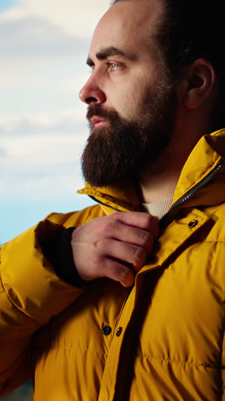 Uomo che si slaccia la giacca e i pantaloni all'aperto con vista sulle montagne