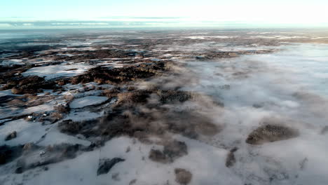 stunning aerial of low mist over expansive snowy countryside landscape