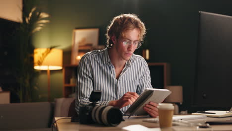 man working with tablet and camera at home