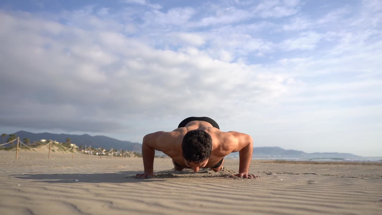shirtless man doing push-ups variant with jump on the beach